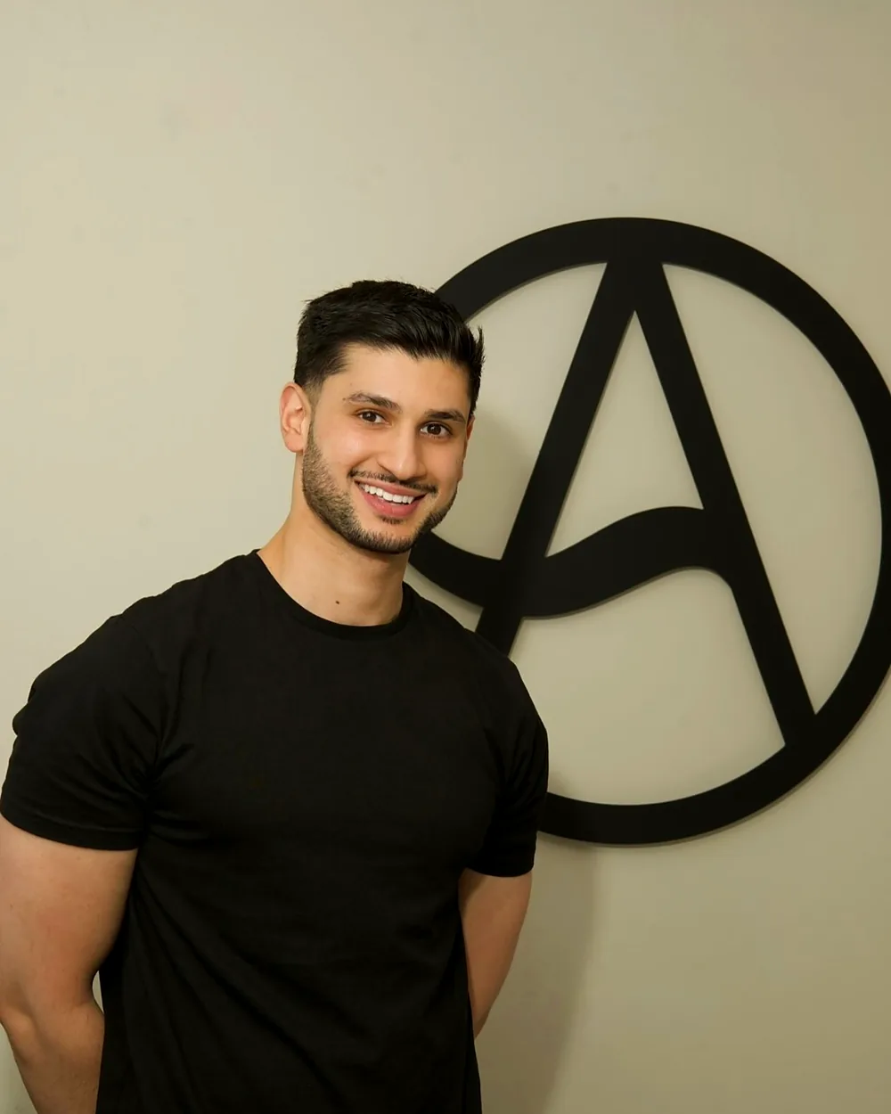 Dr Hisham Saqib, founder of Aura Dental Clinic, in the clinic in front of the Aura logo
